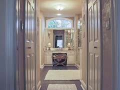 His and Hers Closets Line Entry to Master Suite with Arch Window Above Make-up Station