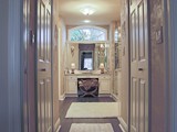 His & Hers Closets Line Entry to Master Suite with Arch Window Above Make-up Station
